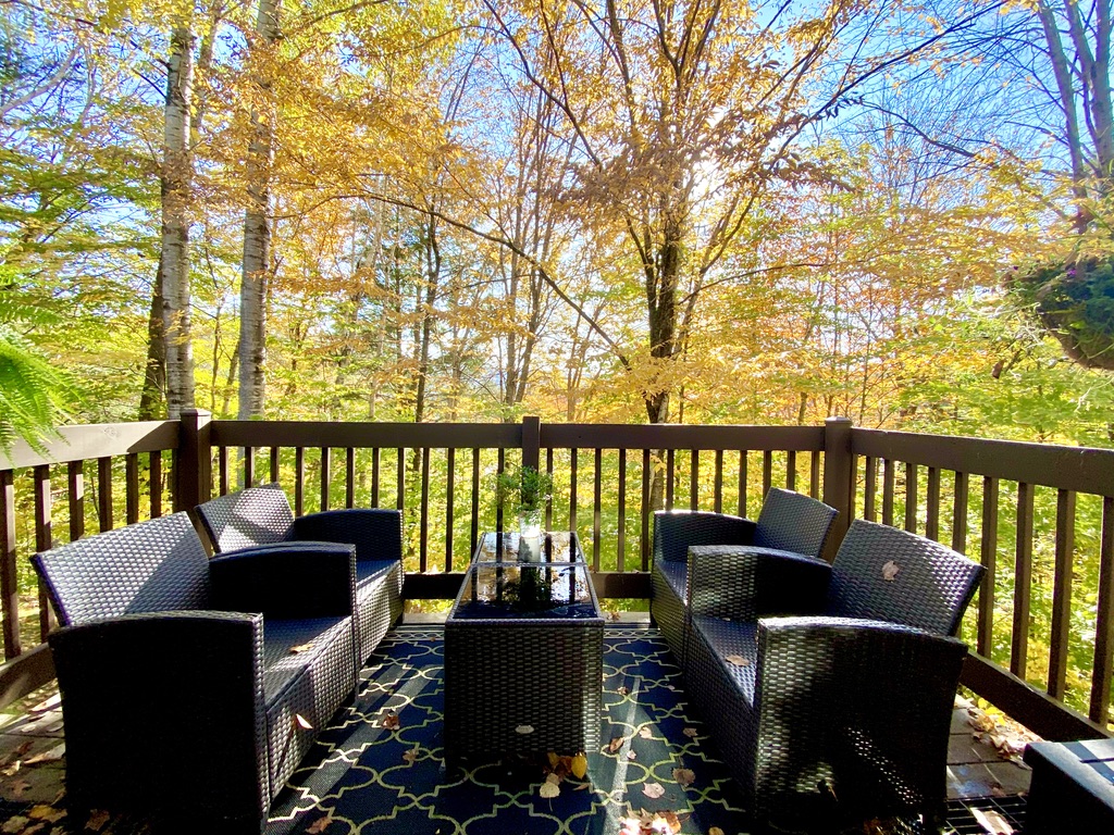 Outdoor deck with wicker seating surrounded by autumn foliage in Woodstock, Vermont